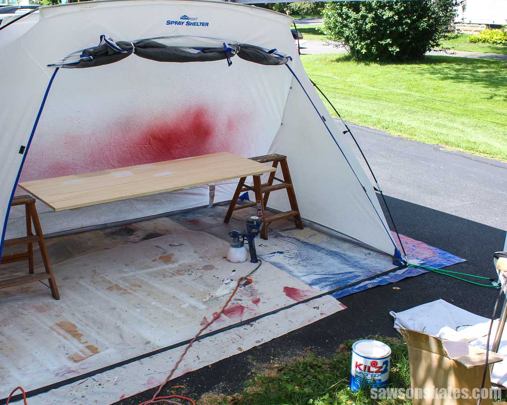 A paint spray shelter set up outside on a driveway with grass in the background
