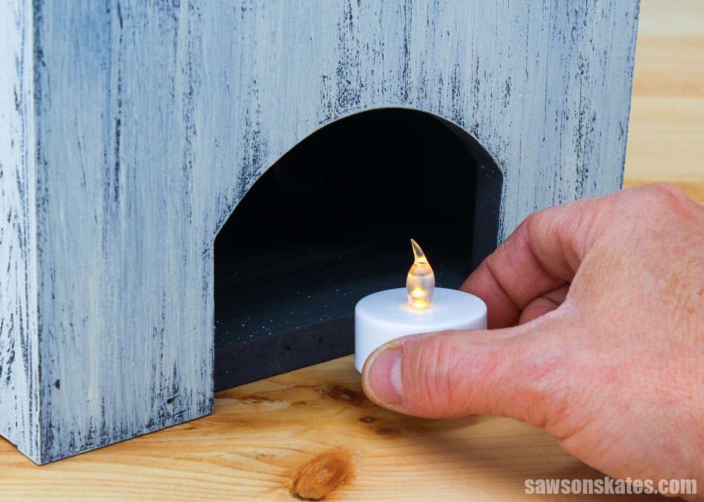 Placing an LED tealight into the back of a wooden DIY ghost lantern