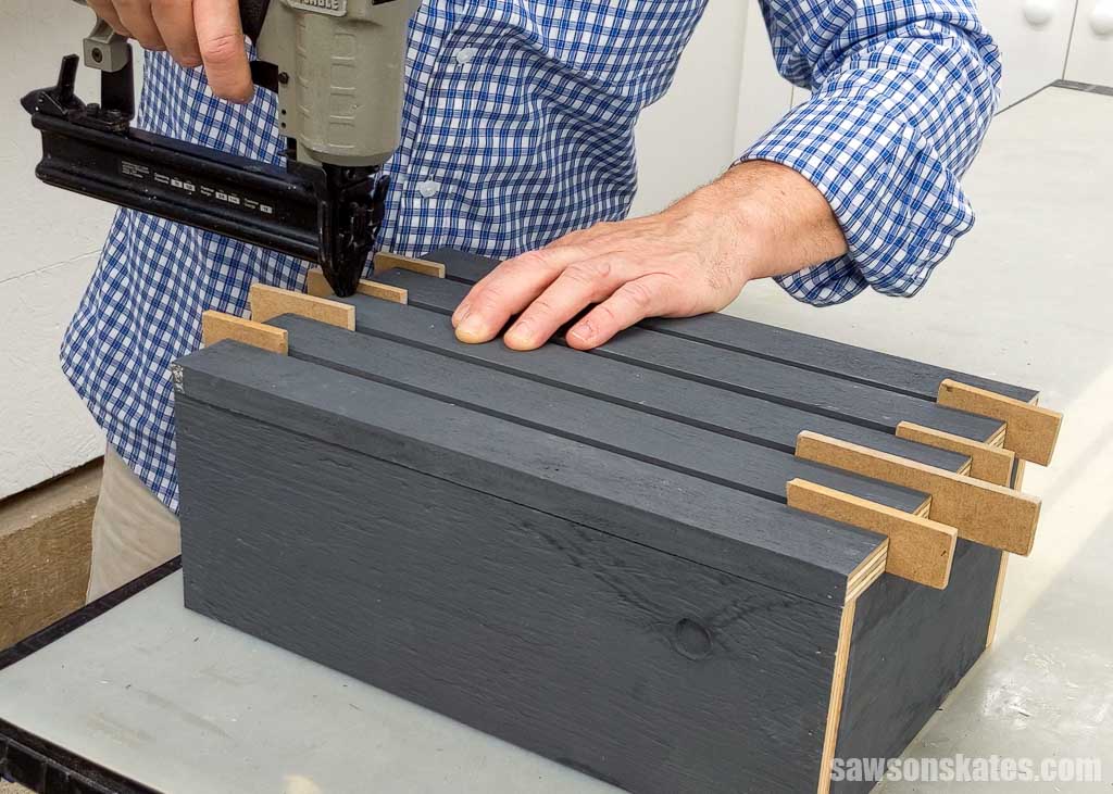 Using a brad nailer to attach the front slats on a wooden DIY ghost lantern