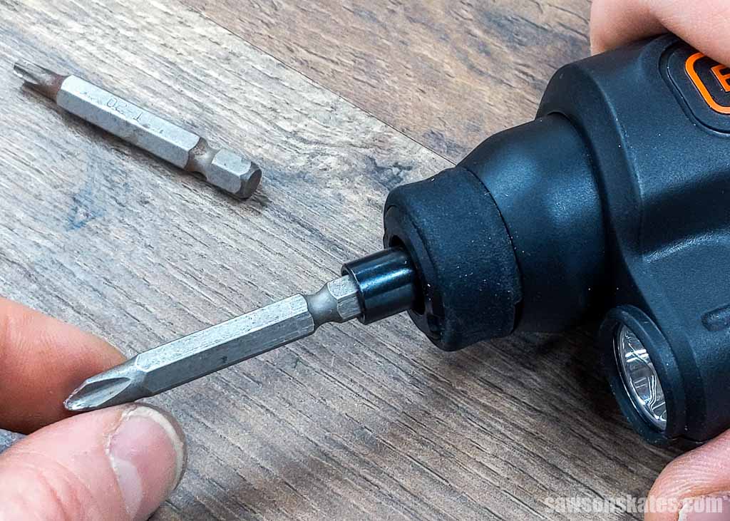 Fingers inserting a phillips bit into a cordless screwdriver