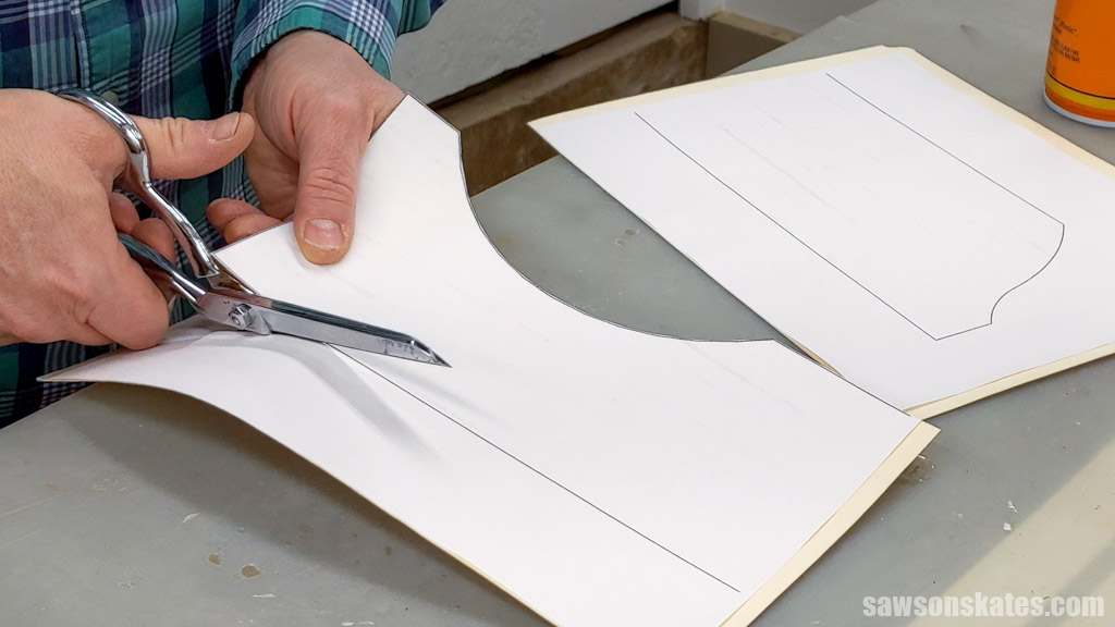 Hands using scissors to cut out a template for a DIY medicine cabinet