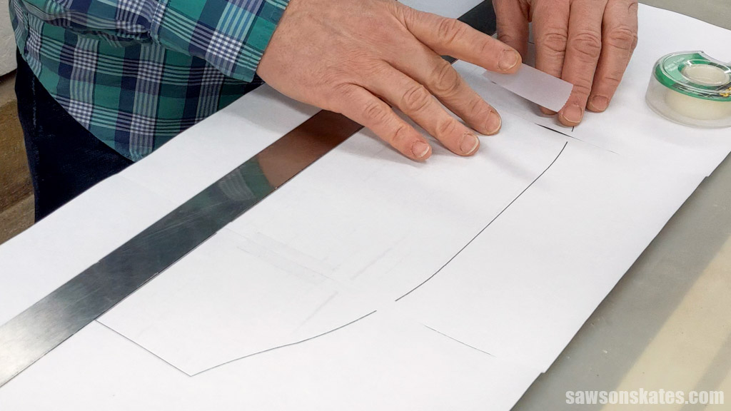 Hands using tape to assemble a pattern for a farmhouse-style DIY medicine cabinet