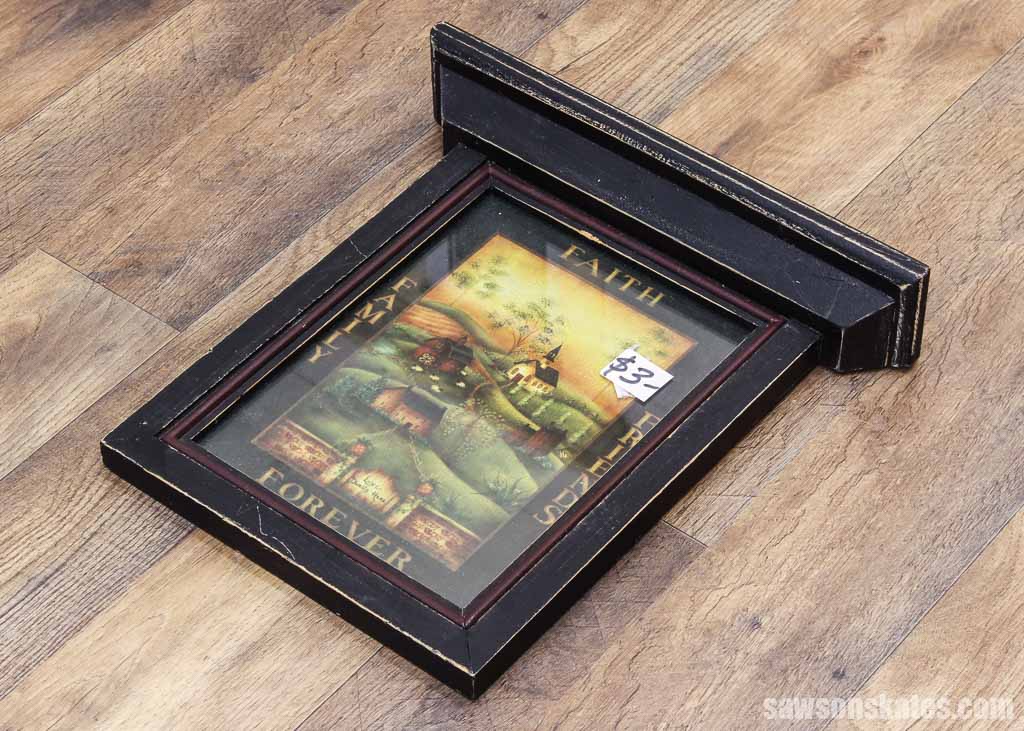 Black picture frame on a wood floor used as inspiration for a DIY picture frame