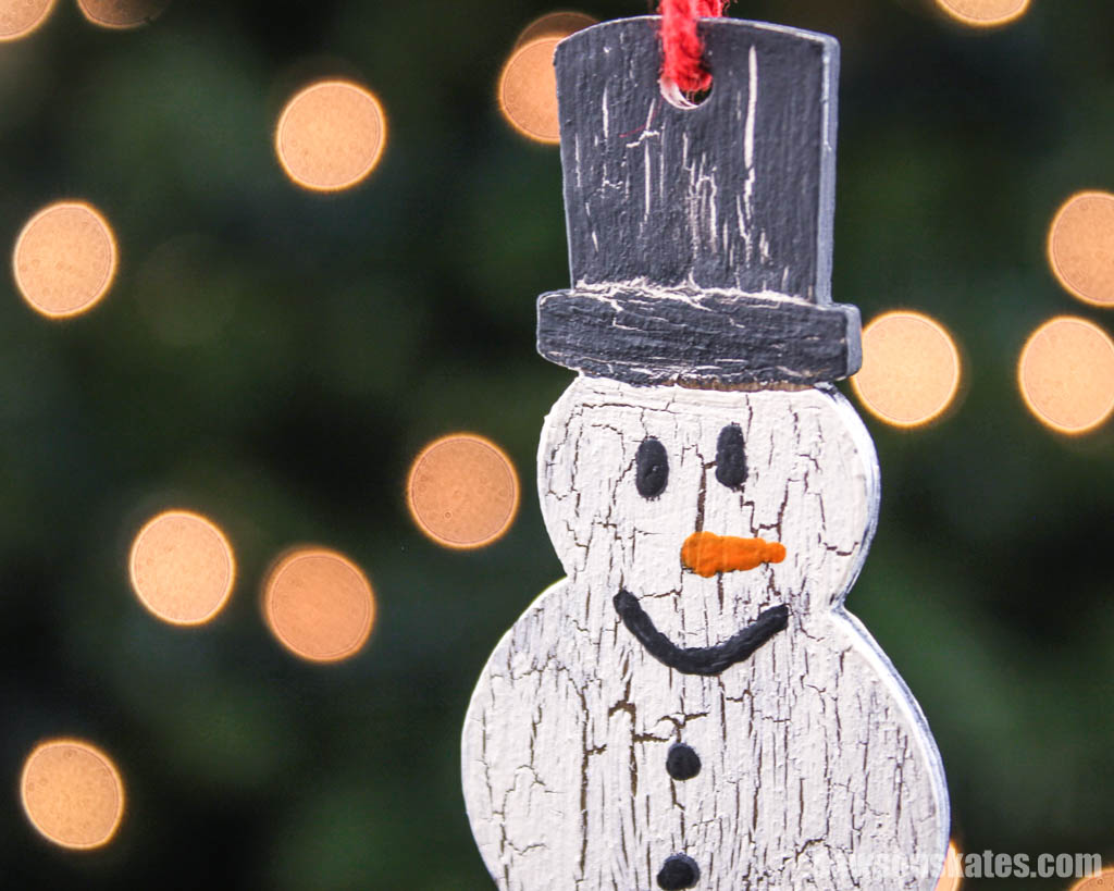 Close up of a wooden DIY snowman Christmas ornament with a crackle paint finish
