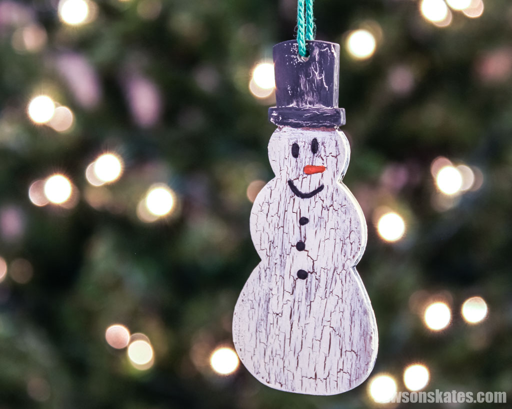 Wooden DIY snowman ornament hanging in a Christmas tree