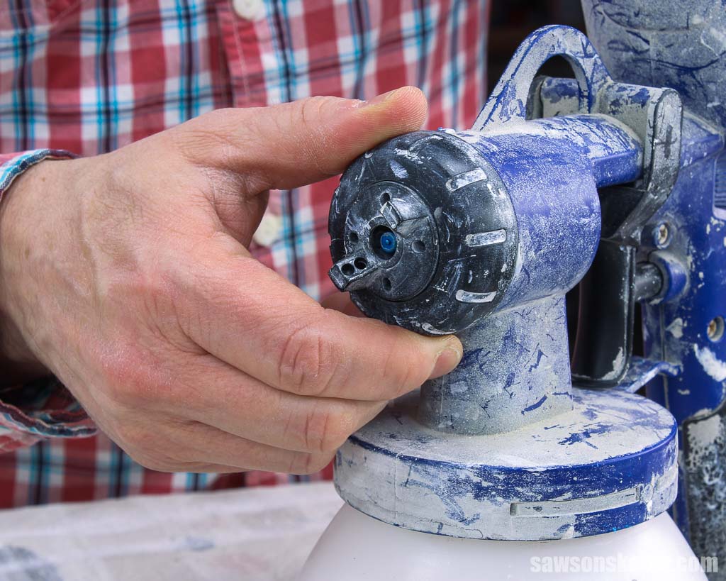 Hand turning a paint sprayer's nozzle