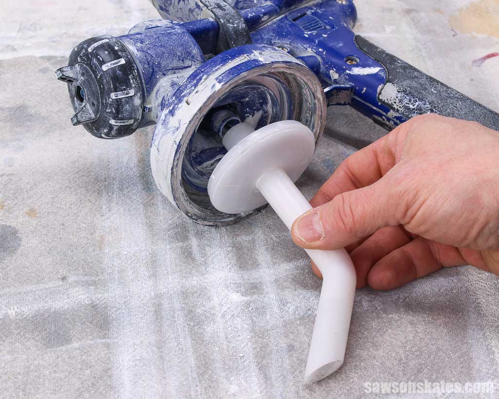 Hand removing a pick up tube from a paint sprayer