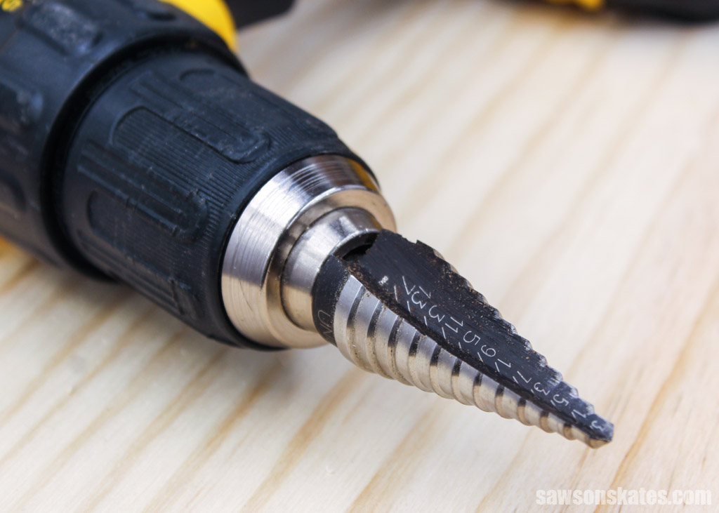 Step drill bit in a drill's chuck on a piece of wood