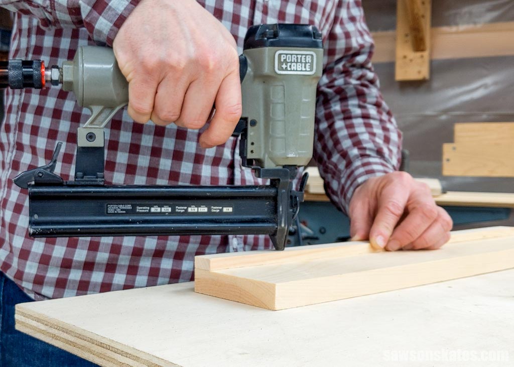 Using a brad nailer to attach a small piece of wood to a larger one