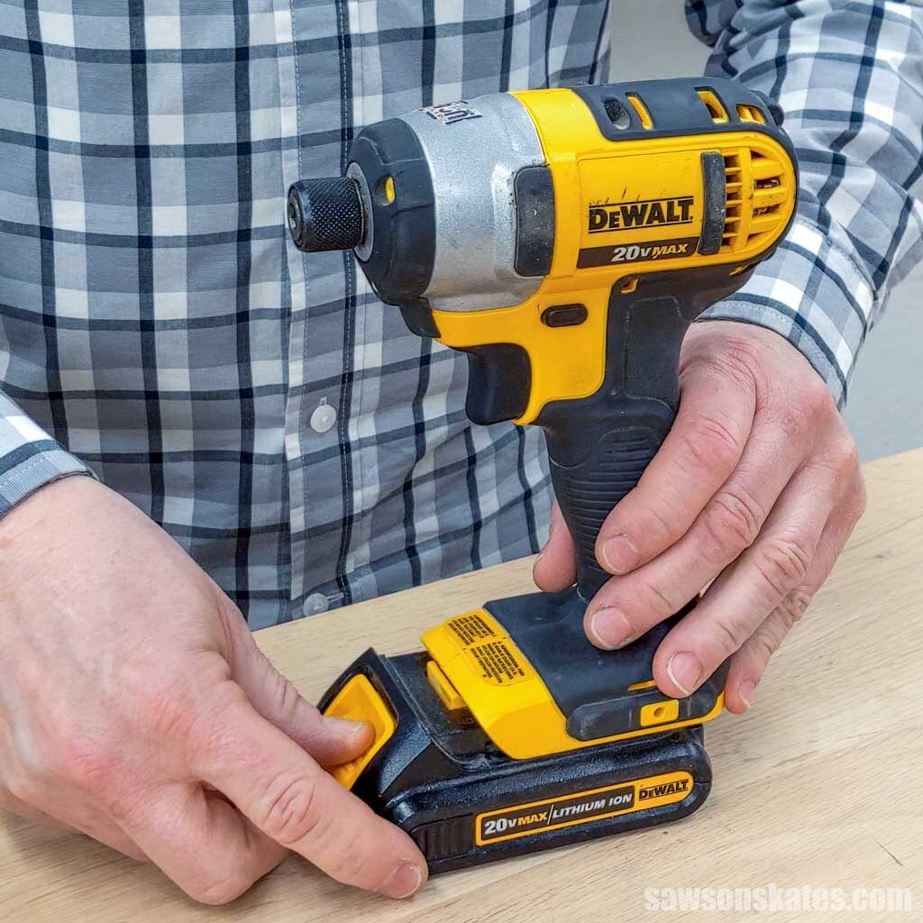 Hand removing a battery from an impact driver