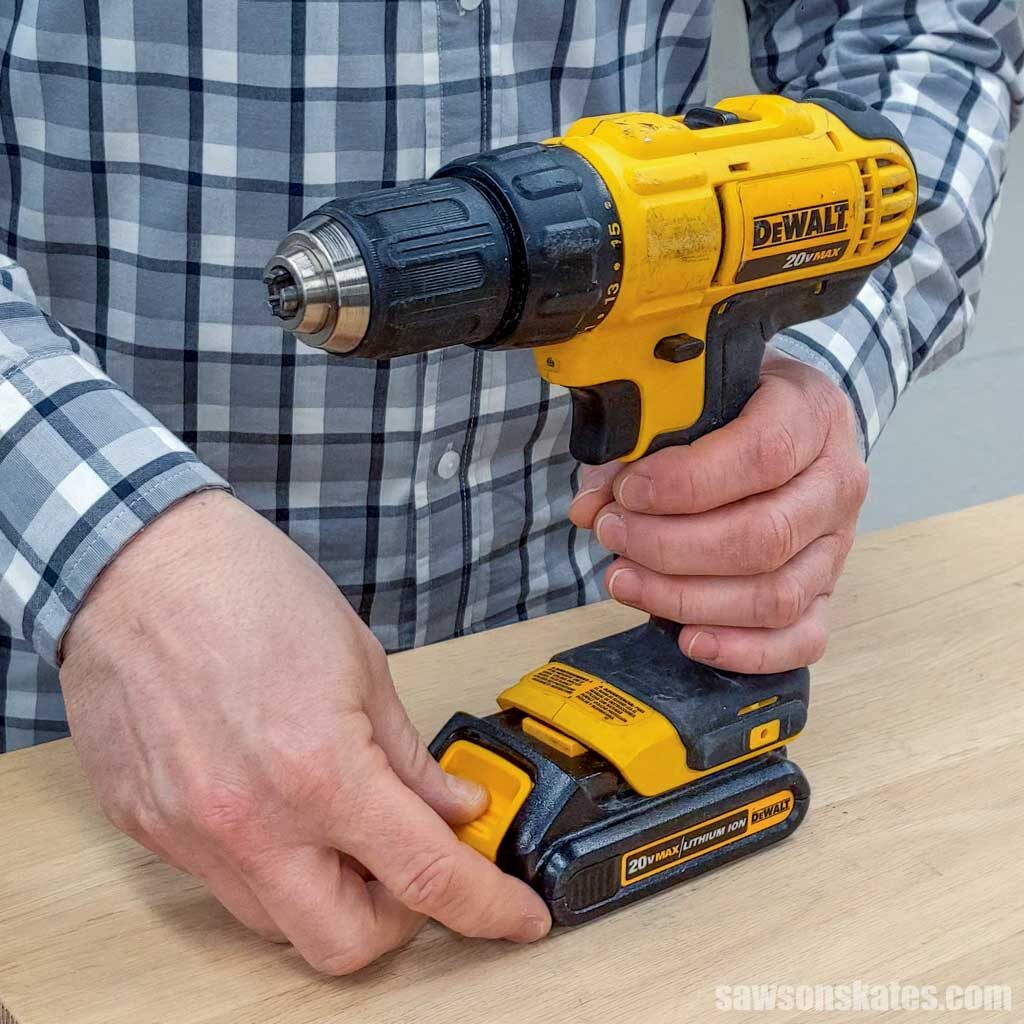 Hand removing a battery from a drill