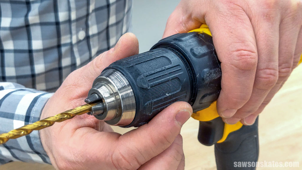 Hands tightening a drill's jaws around a drill bit