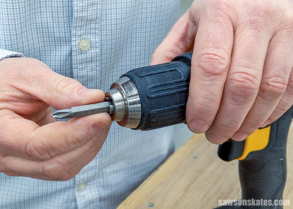 Hand inserting a driver bit into a drill