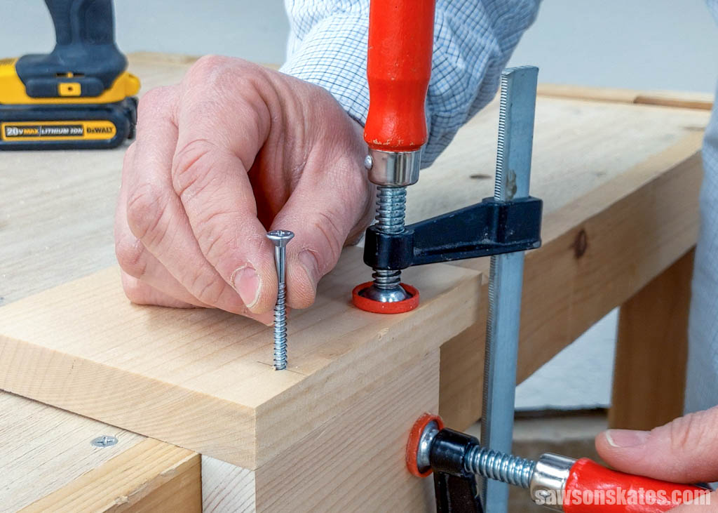 Hand inserting a screw into hole made by a drill