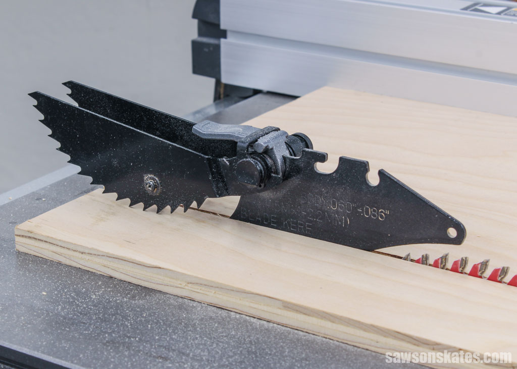 A table saw's anti-kickback pawls resting on a piece of plywood
