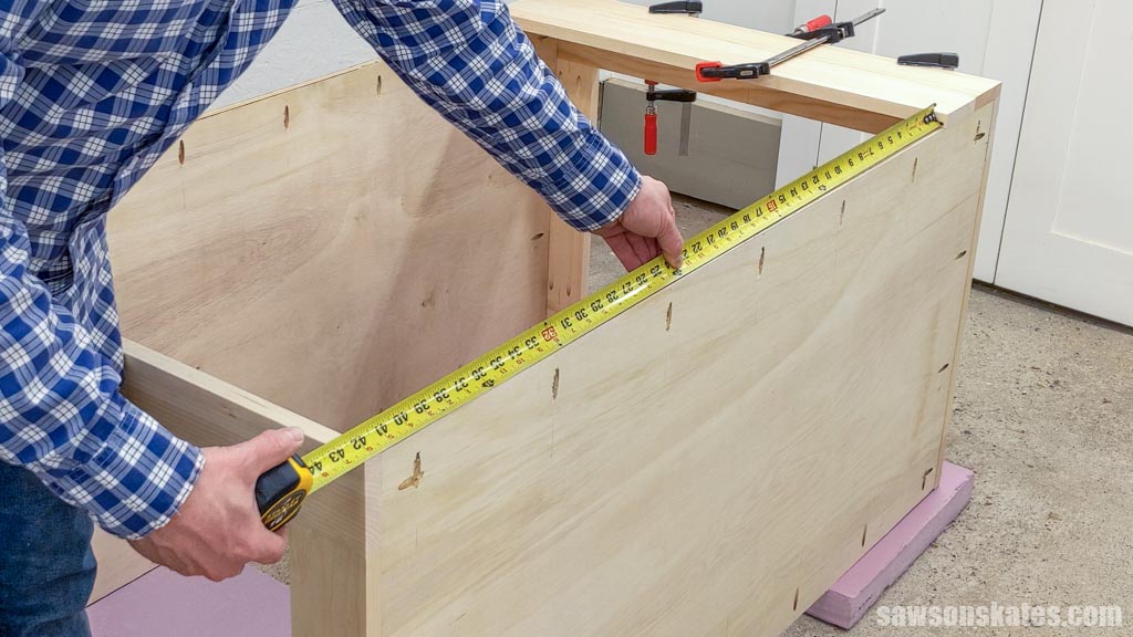 Using a tape measure to measure the side assembly of a DIY rolling shop cart