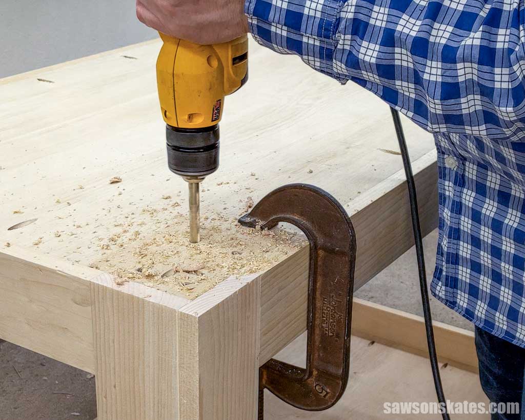 Using a drill to make a hole in the bottom of a DIY utility cart