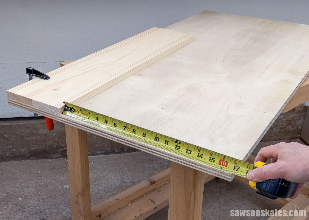 Using a tape measure to measure a piece of plywood