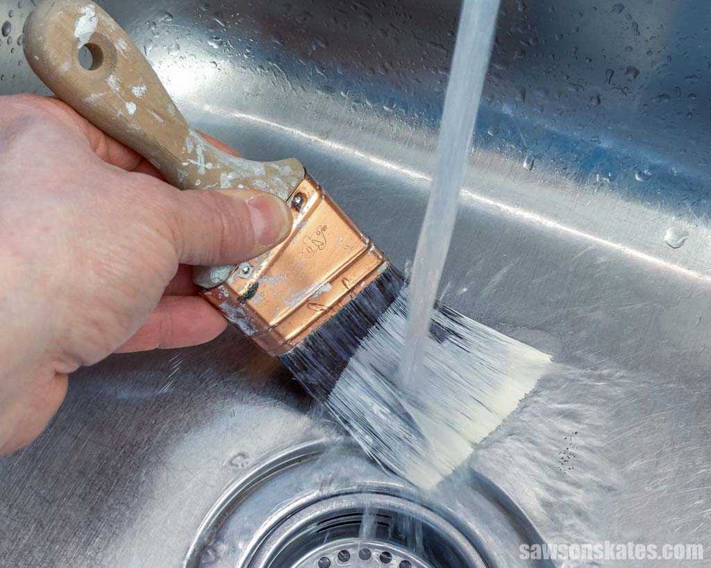 Washing a paint brush in a sink under running water