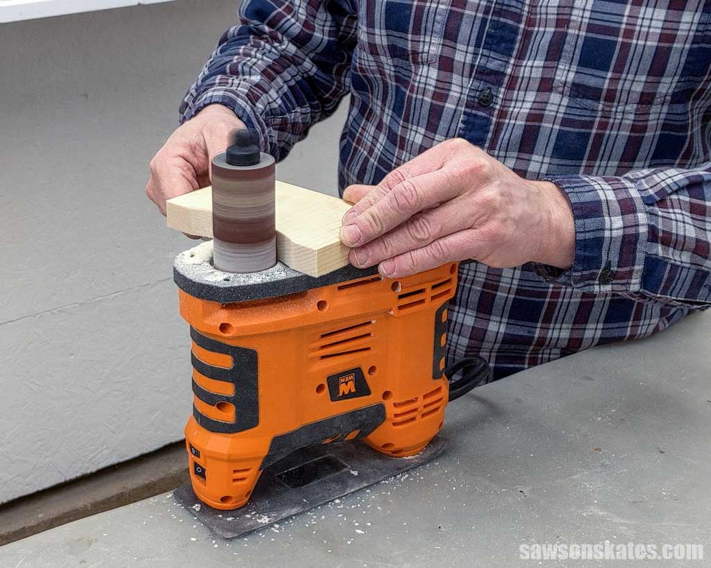 Using a portable spindle sander to smooth the edges of a DIY dog bowl stand's leg