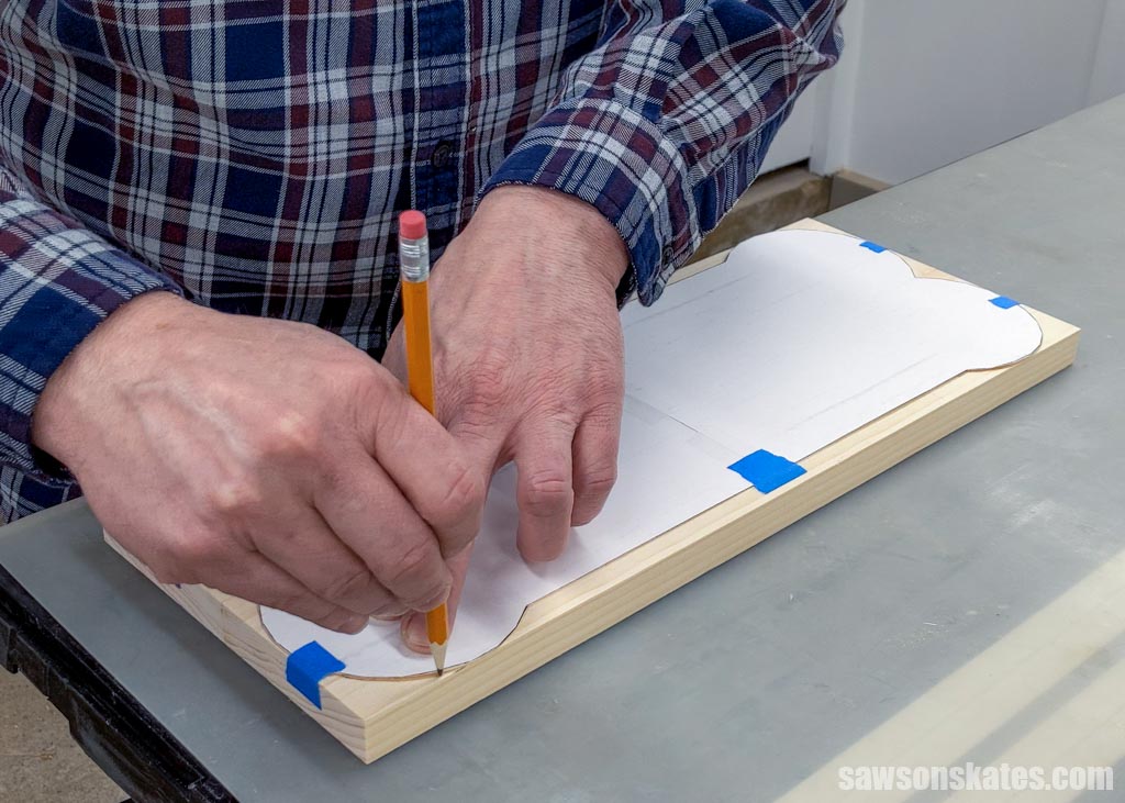 Using a pencil to trace a bone-shaped template onto a board