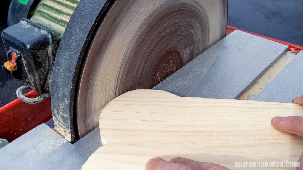Using a disc sander to smooth the edges of a DIY dog bowl stand's bone-shaped-top