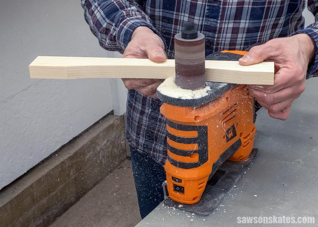 Using a spindle sander to smooth the edges of a DIY dog bowl stand's rail