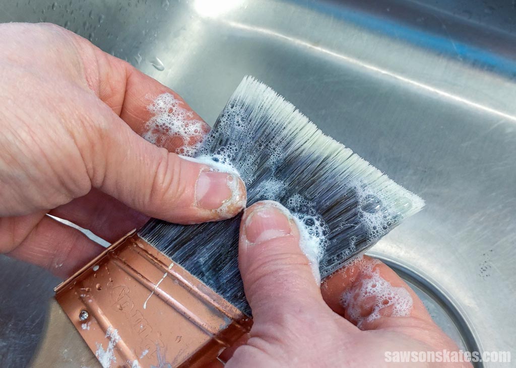 Fingers massaging soap into a paint brush's bristles