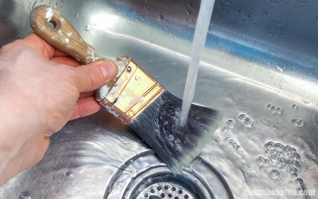 Rinsing a paint brush in a sink under running water