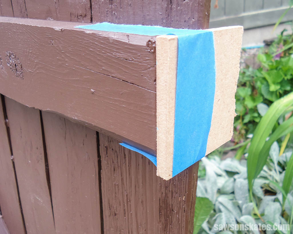 Shim attached with painter's tape to a DIY garden gate's rail
