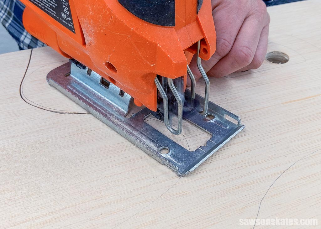 Using a jigsaw to cut a DIY cord holder out of a piece of plywood