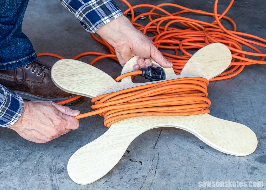 Hands winding an extension cord around a DIY cord holder