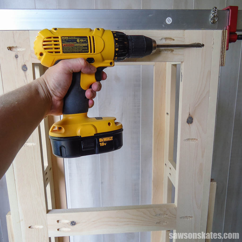 Using a drill to attach an outdoor plant stand's back frame to its side assembly