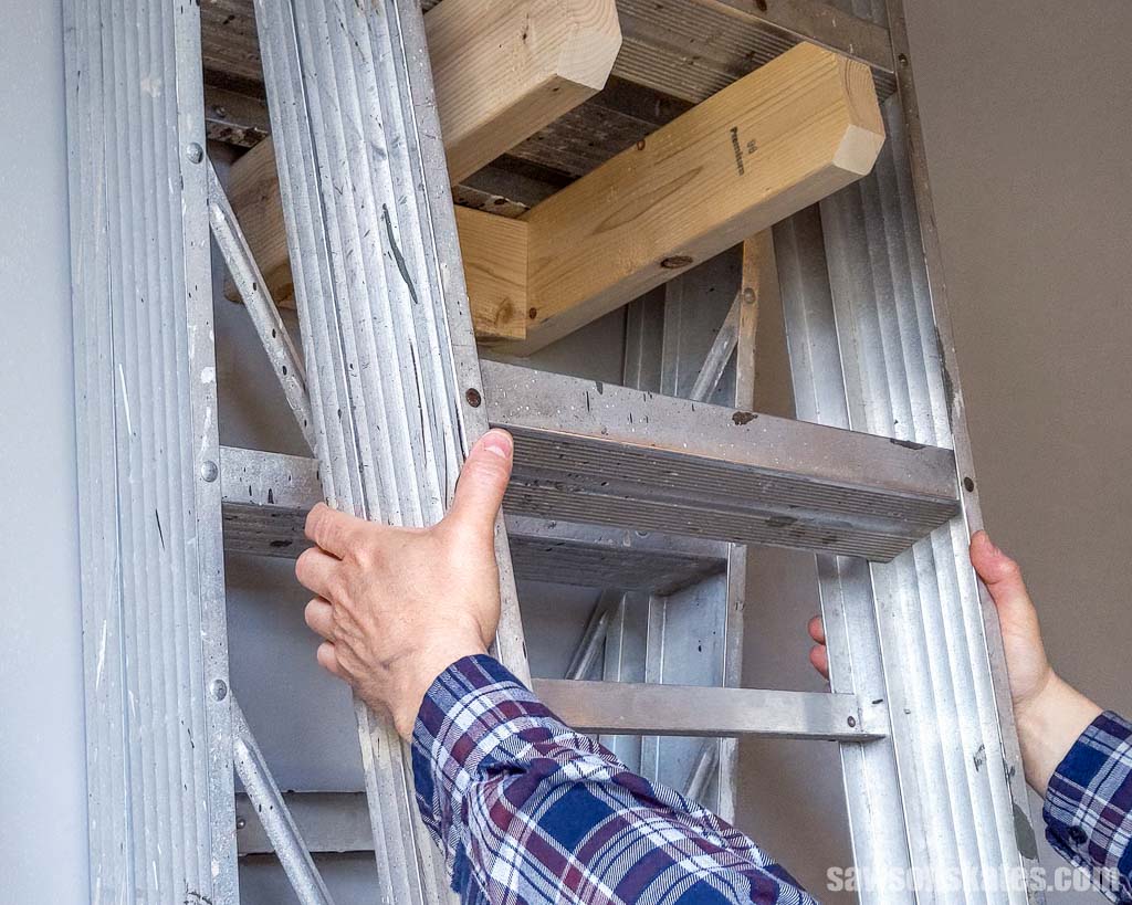 Hands removing a ladder from DIY ladder hooks
