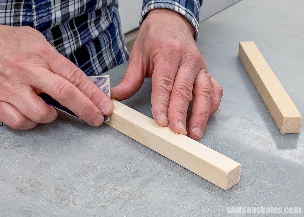 Using sandpaper to knock off a board's sharp edges, giving it a more log cabin-like appearance.