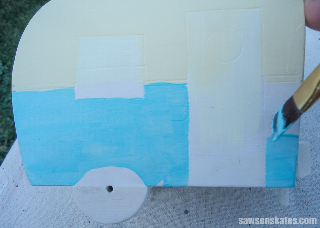 Using a small brush to paint the sides of a DIY vintage camper napkin holder