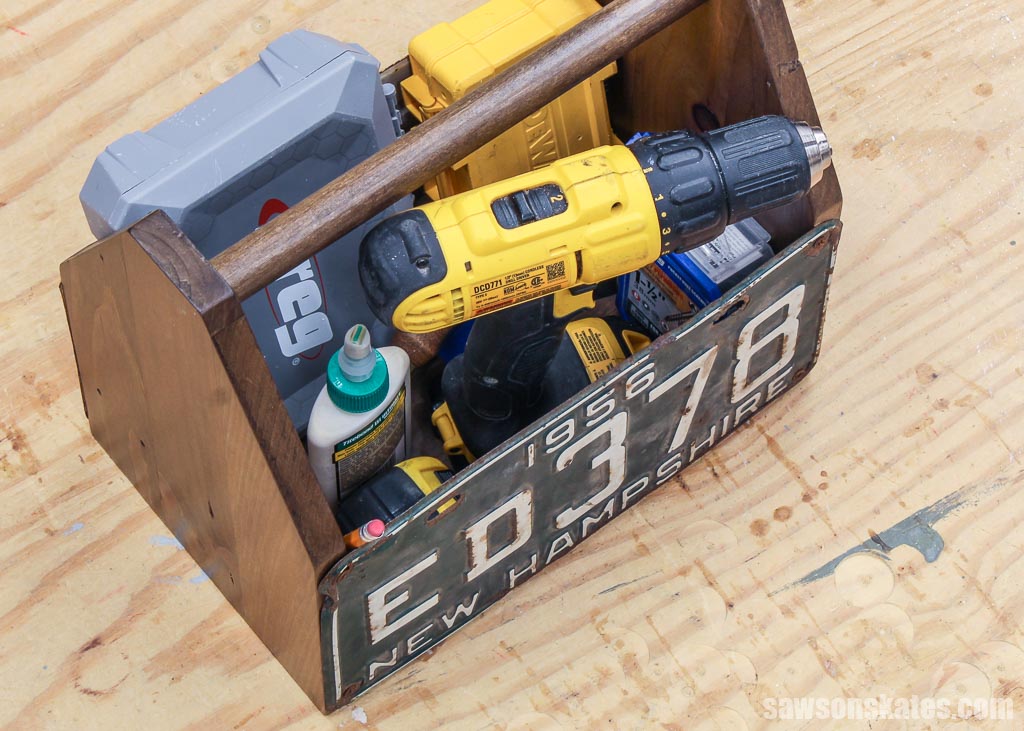 Overhead view of a DIY tool tote filled with a drill, glue bottle and more