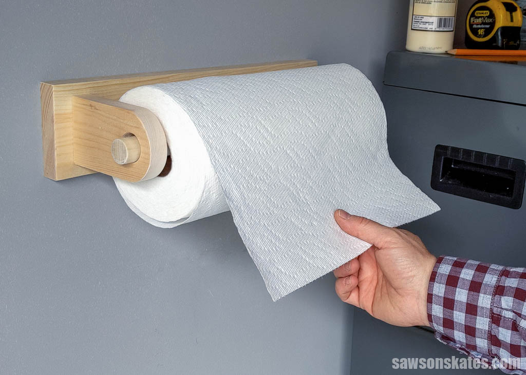 Hand pulling paper towel from a DIY workshop paper towel holder