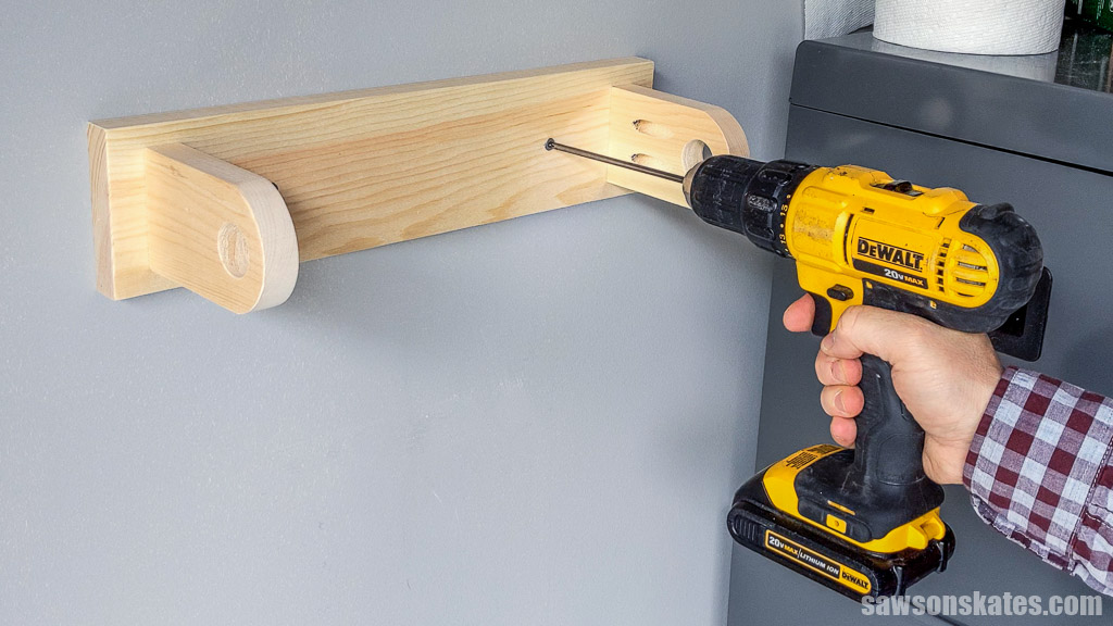 Attaching a DIY workshop paper towel holder to the wall with a screw