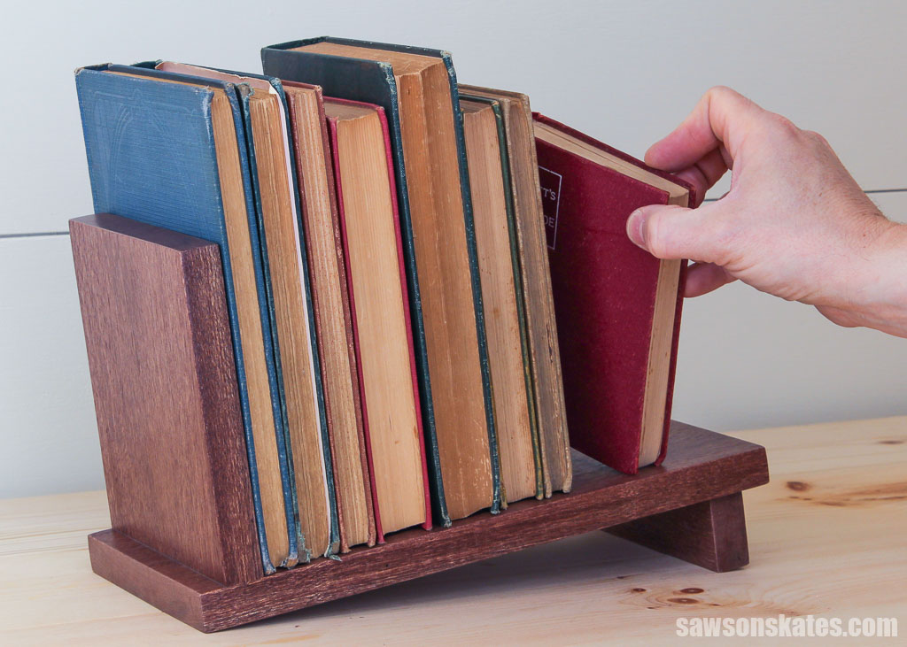 Hand removing a book from an easy-to-make wood book rack