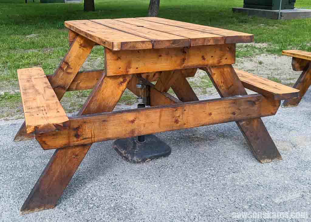 Simple wood picnic table with trees in the background
