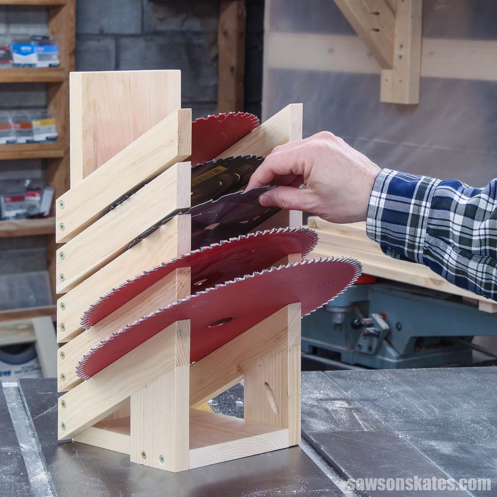 Hand placing a saw blade into an easy to-make saw blade storage rack