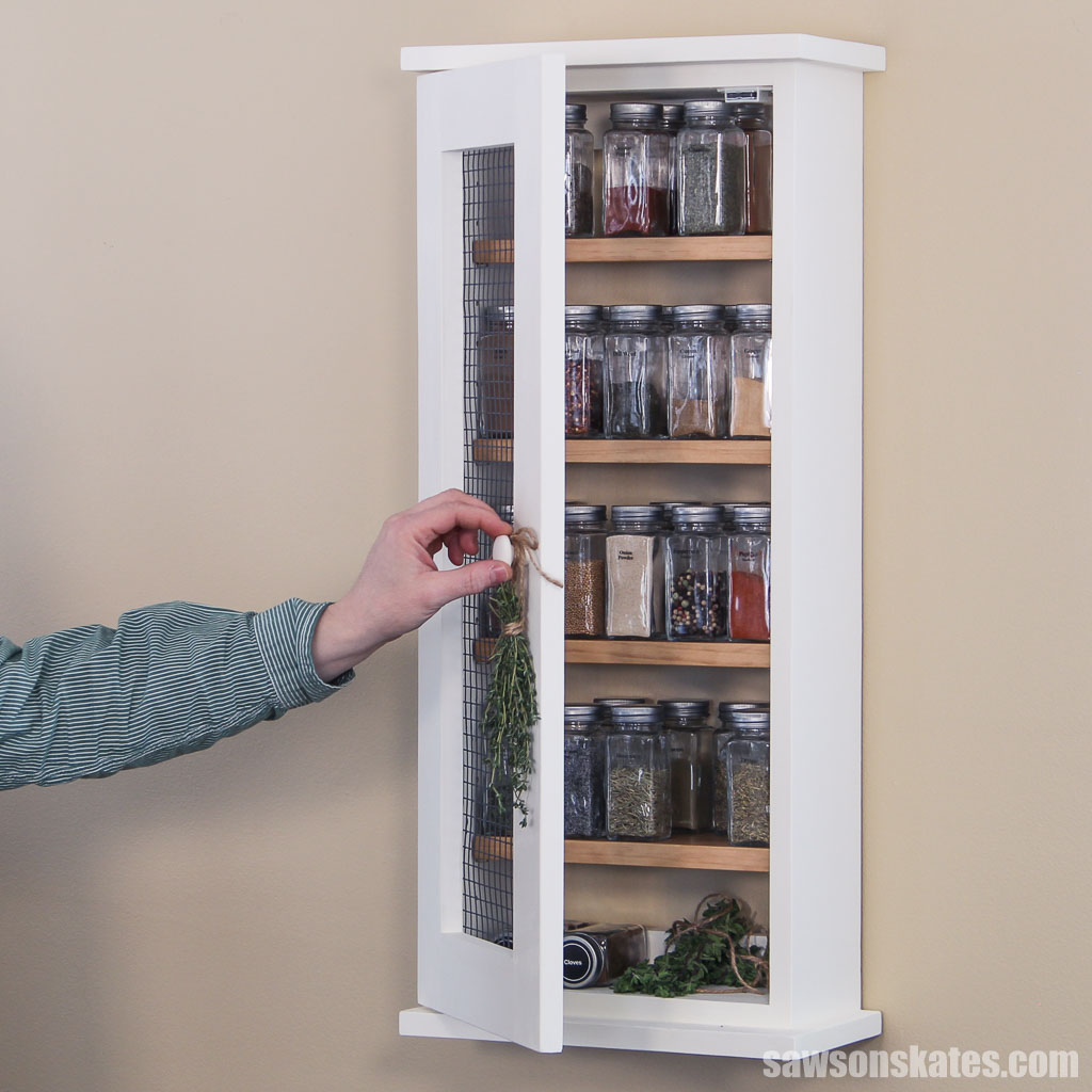 Hand opening an easy wall-mounted spice cabinet