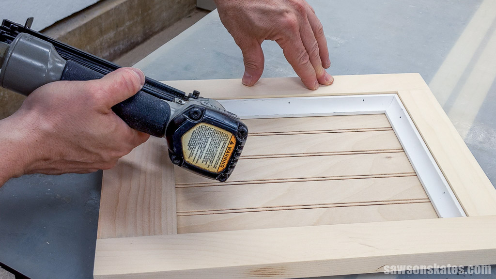 Using a brad nailer to attach the second piece of molding to the door