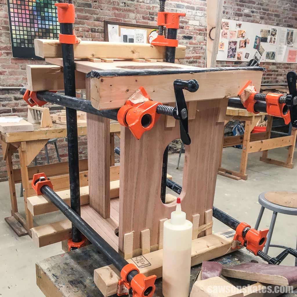 A footstool or bench being assembled with clamps at a woodworking class