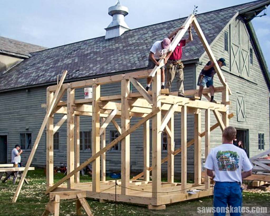 Attendees at a timber frame woodworking class assembling a small building