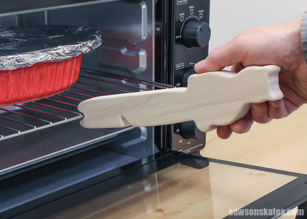 Hand using a cat-shaped DIY oven rack puller to push in an rack