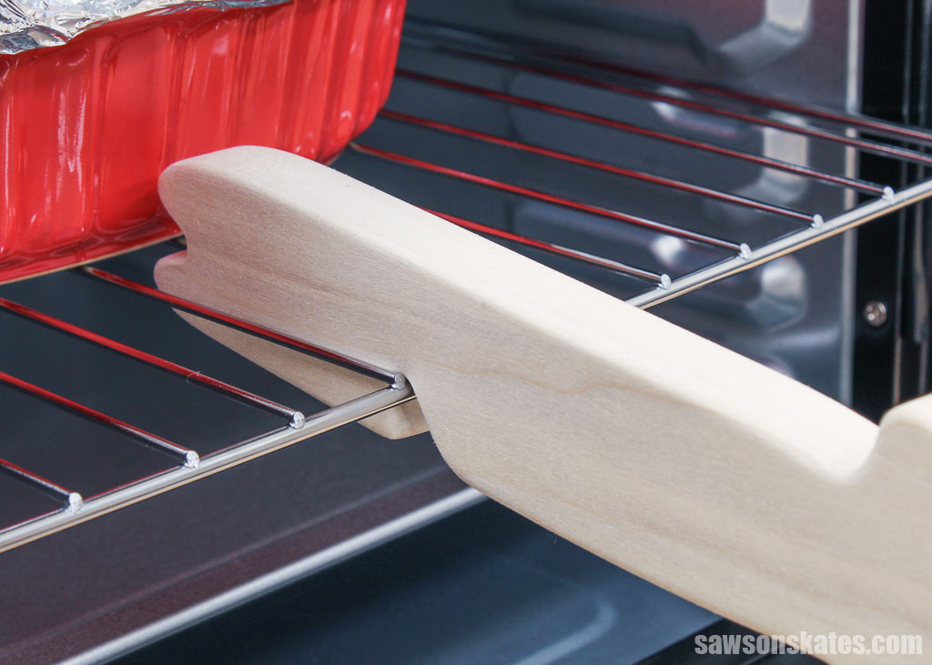 Close up of a DIY wooden oven rack push pull stick pulling out a rack