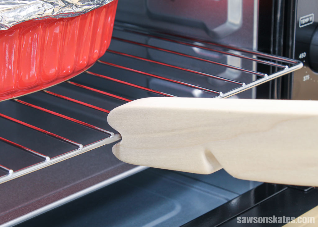 Close up of a DIY oven rack puller pushing in an oven rack