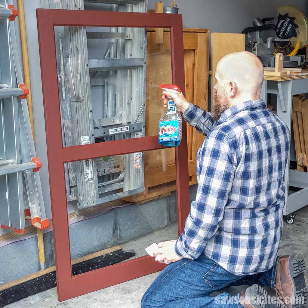 Spraying glass cleaner on a DIY wood storm window